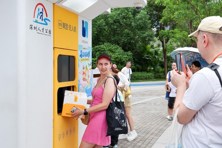지난 3일 광둥(廣東)성 선전(深圳)시 런차이(人才)공원에서 메이퇀(美團)의 드론 배송을 체험하는 해외 관광객. (사진/신화통신)